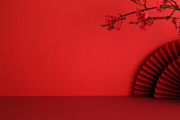 Minimalist Chinese New Year background with traditional red color, pleated paper fan, and plum...