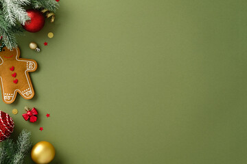 Flat lay of festive arrangement with a gingerbread man cookie, fir branches, red and gold ornaments...