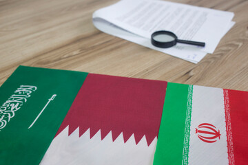 Saudi Arabia, Qatar and Iran flags with documents in the office desk