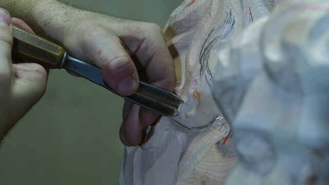 Skilled carpenter carving intricate wooden sculpture with a chisel