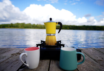 Making coffee on portable camping gas burner at lake. Brewing coffee outdoors on gas stove at lake....