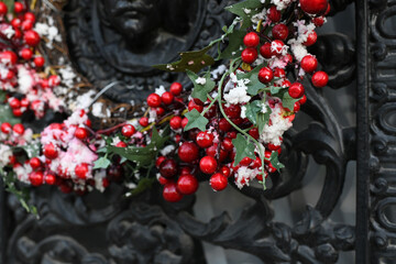 The red berries on a Christmas wreath on a metal door