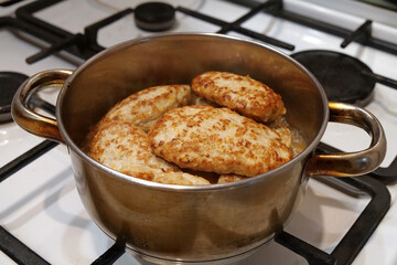 Meat cutlets are stewed in saucepan after being fried in a frying pan