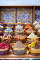 Traditional spices market. Pots and wooden tubs stand in row with colorful tea, spices, fruits, roots, flowers. Street bazaar. Dubai, UAE. Vertical photo
