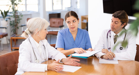 three doctors are sitting at table animatedly and actively discussing work
