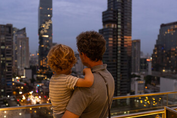 Obraz premium family trip to Bangkok, parent with child looking at modern buildings in Bangkok, Thailand by night, viewpoint