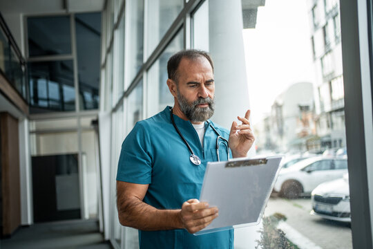 Doctor reviewing medical chart planning patient care - Powered by Adobe