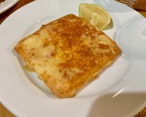 fried feta cheese with lemon on a plate