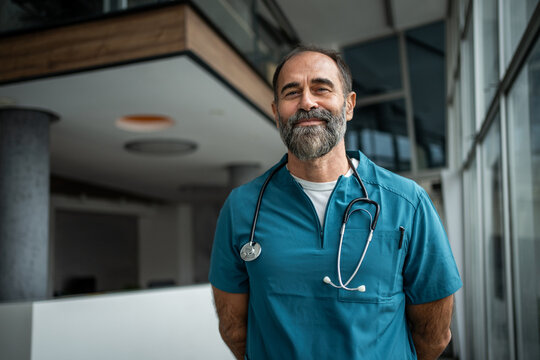 Experienced male doctor smiling in hospital corridor