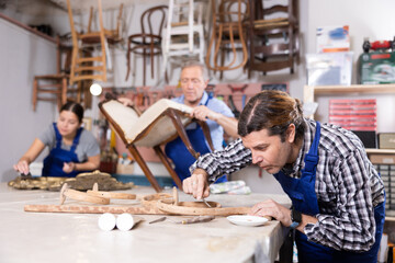 Portrait of middle-aged skillful repairman carpenter renovating chair furniture using tools in woodwork studio