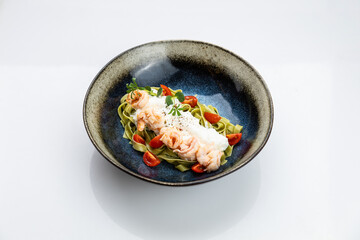 Gourmet spinach tagliatelle with shrimp, burrata and cherry tomatoes in ceramic bowl