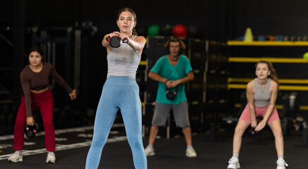 Sportive young woman practicing with kettlebell in exercise room during weight training classes