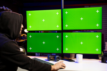 Hacker using green screen computer displays to extract military secrets data from secure digital systems. Cybercriminal using chroma key multi monitor PC setup, running espionage software
