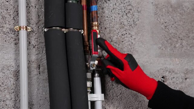 Gros plan sur une main en train d'indiquer une vanne d'eau de canalisation en plomberie dans une maison.