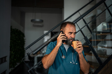 Doctor having coffee break using mobile phone
