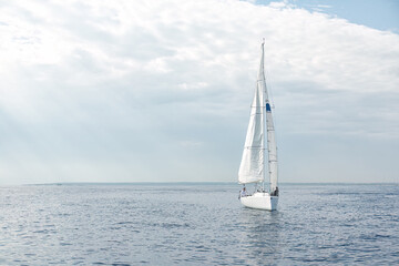 Sailboat sailing in the sea with sails up on a cloudy day