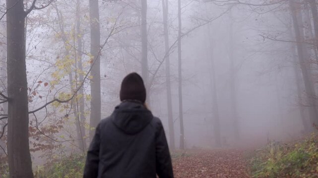 Cinematic 4K shot of woman walking in foggy forest, lower-third framing
