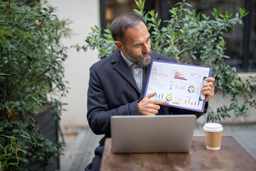 Mature businessman explaining data charts during outdoor meeting