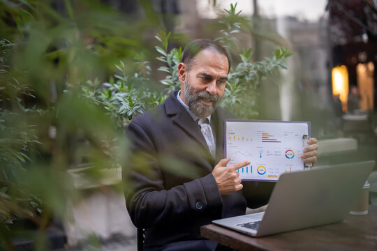Mature businessman presenting data during outdoor video conference