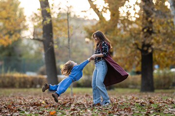 Mother spinning daughter around in autumn park