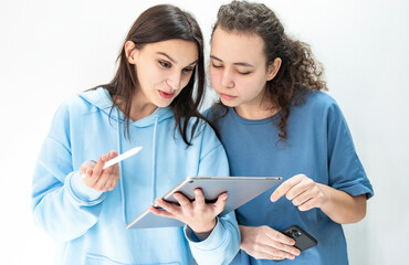 Friends collaborating on project while using modern technology. Girls with gadgets