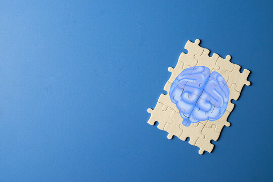 Brain icon on jigsaw puzzle. Mental health, psychology, Alzheimer's, or problem-solving and solution concept. Neurology and memory care. Blue background with copy space.