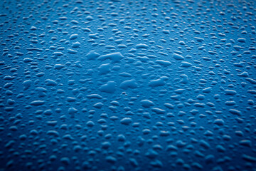 Abstract close up view of rain drops on blue metallic background