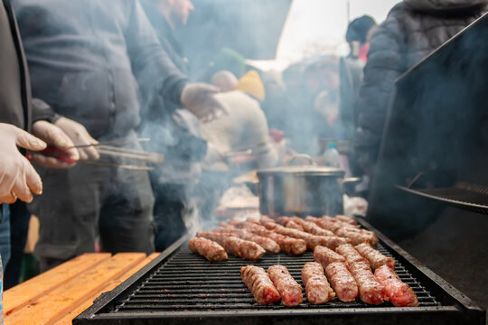 People grilling traditional mici at an outdoor street food festival