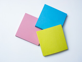 Three colorful sticky note pads—blue, yellow, and pink—stacked on a white background. 