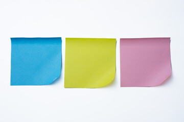 Three sticky notes in blue, yellow, and pink aligned side by side on a white background. 