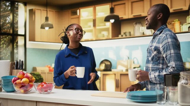 African american lovers serving fresh coffee cups and chatting in the kitchen, enjoying golden toast and homemade pastry. Jolly expressions capture good vibes during morning breakfast. Camera A.