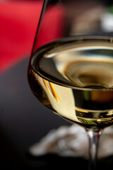 A fine glass of golden wine rests elegantly on a black surface, capturing light beautifully. The rich color invites savoring moments of relaxation and conversation, perfect for any occasion