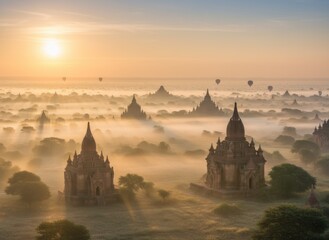 Ancient temples emerge from morning mist, silhouetted against a sunrise with hot air balloons