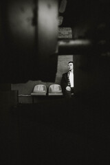 A lone figure sits in a shadowy environment, surrounded by muted colors. The atmosphere conveys...