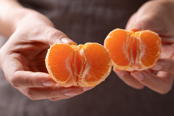 Mandarin orange fruit holding by hand and eating