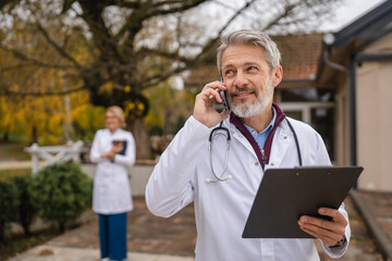 Senior doctor talking on phone while walking outdoors
