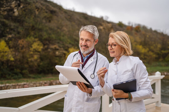 Doctors collaborating on medical chart outdoors discussing healthcare