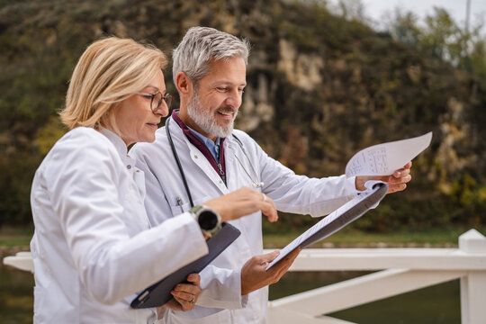 Medical professionals discussing patient charts outdoors - Powered by Adobe