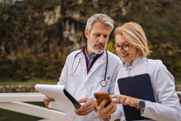 Doctors discussing medical data using modern technology outdoors