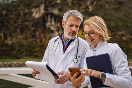 Doctors discussing medical data using modern technology outdoors
