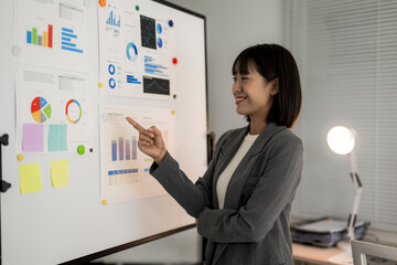 Smiling businesswoman presenting business data charts on whiteboard