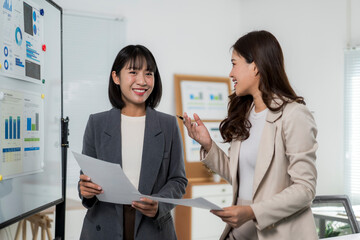 Two asian businesswomen discussing charts and data during a corporate meeting