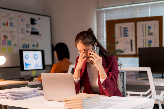 Stressed asian businesswoman having headache from phone call