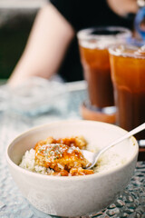 Delicious meal of rice, chicken, and sauce served in a bowl with iced tea on a glass table