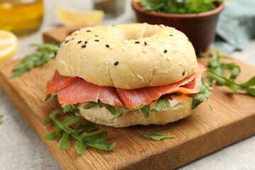 Delicious bagel with salmon and arugula on grey table, closeup