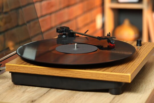 Modern turntable with vinyl record at home, closeup