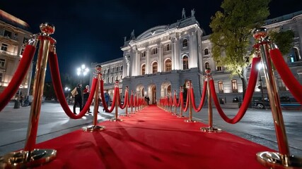 Elegant Red Carpet Event: A glamorous red carpet, framed by polished gold stanchions and velvet ropes, stretches towards a distinguished building at night.