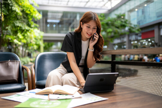 Asian businesswoman multitasking, talking on phone and using tablet