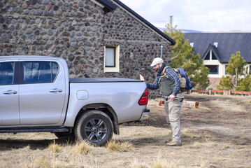 A young Hispanic traveler closes the trunk of his pickup truck to begin a hike. He is ready to go...