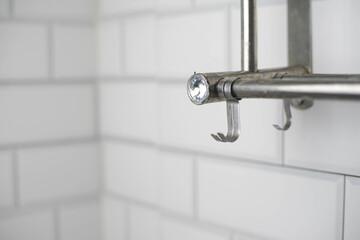 Modern metal towel or utensil rack with hooks and a sparkling crystal accent against a clean white subway tiled wall. Bathroom or kitchen decor.